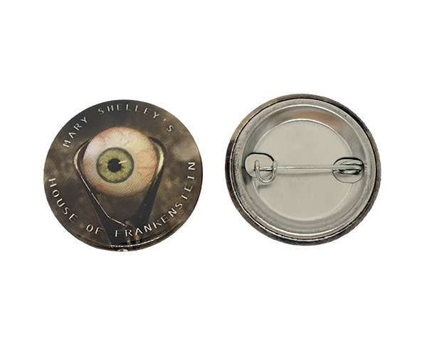 Two 32mm Button Badges: one displays an illustration of an eyeball with the text “Mary Shelley’s House of Frankenstein,” whilst the other reveals the metal back and clasp.