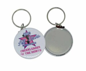 Two keychains are shown; one displays “HRC All Stars Cheerleading CHEERLEADER OF THE MONTH” with a star graphic, and the other side is blank and metallic.