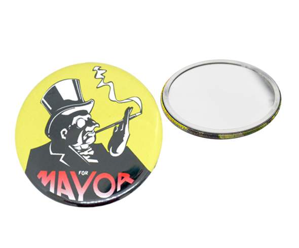 A round pin-back button features a cartoon man in a top hat and monocle smoking, with the words "FOR MAYOR" in bold letters below. Another button is shown with the blank back facing up.
