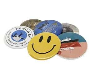 A set of six 58mm Button Badges featuring assorted designs, such as a yellow smiley face, a ship, a gorilla, and text representing the New Haven Historical Society and Museum.