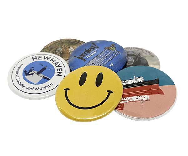 A set of six 58mm Button Badges featuring assorted designs, such as a yellow smiley face, a ship, a gorilla, and text representing the New Haven Historical Society and Museum.
