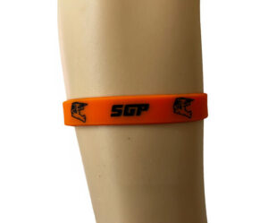An orange silicone wristband with black text "SGP" and two outlined wolf head logos, worn on a mannequin's arm.