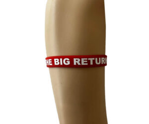 A red wristband with white text reading "THE BIG RETURN" is worn on a person's forearm against a plain background.