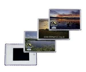 Four rectangular acrylic fridge magnets, three featuring nature scenes and logos, one turned over to display the reverse side.