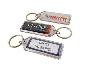 Three rectangular Acrylic Keyrings (50mm x 20mm Lozenge) are shown, each with a different label: “CJ HOLE,” “OFFICE THERAPIST,” and one with a partially visible logo and text.