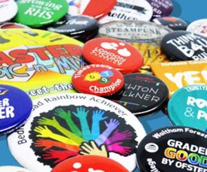 A variety of colorful pin badges with different designs and texts are scattered across a blue surface.