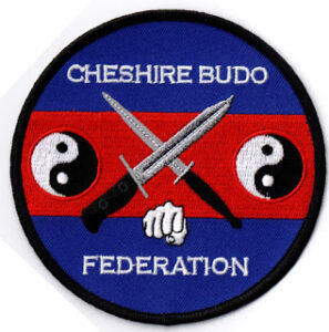 A circular patch with "Cheshire Budo Federation" text, two crossed knives, a fist, and two yin-yang symbols on a red and blue background.