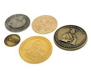 Five commemorative coins of varying sizes and colours are arranged on a white background, each featuring unique designs and inscriptions.