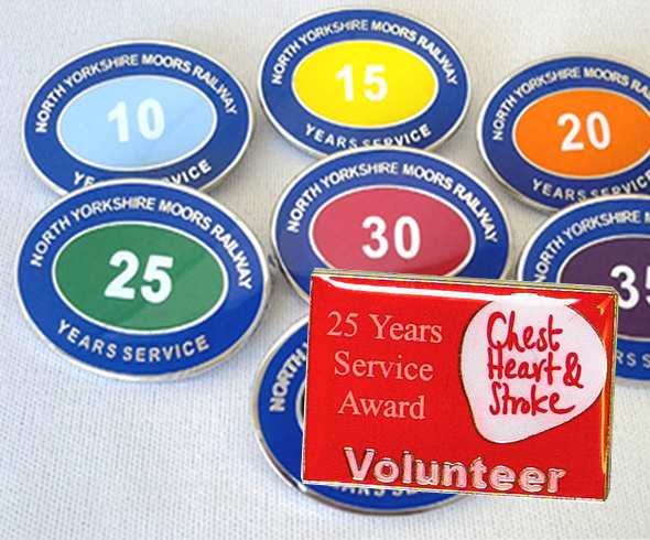 Assorted service award badges for North Yorkshire Moors Railway, with a red badge in front for 25 years' volunteer service at Chest Heart & Stroke.