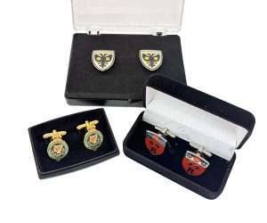 Three pairs of Enamelled Cufflinks in black display boxes, each featuring different shield and crest designs with various colours.