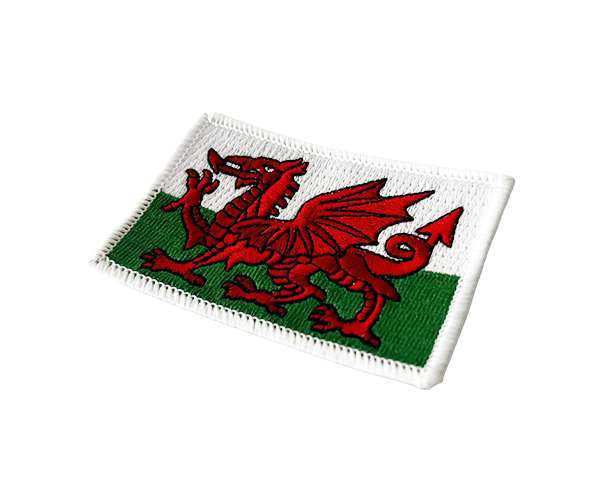 Embroidered with the iconic red dragon on a white and green background, the Welsh (Wales) Flag Embroidered Badge is photographed on a white surface—this eye-catching patch is ideal for displaying your national pride.