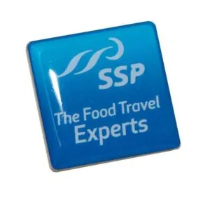 A blue square pin with the white SSP logo and the text "The Food Travel Experts" printed on it.