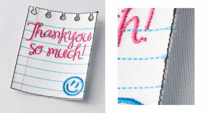 A fabric patch shaped like a piece of notebook paper with blue lines and pink text reading "Thank you so much!" next to a blue smiley face.