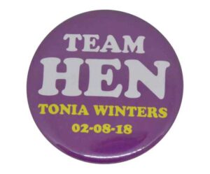 Purple button badge with white text "TEAM HEN" and yellow text "TONIA WINTERS 02-08-18" printed on it.