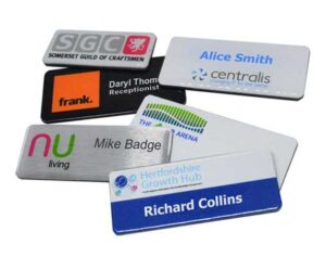 A selection of six rectangular name badges with various colors, logos, and text, displaying different names and company affiliations.
