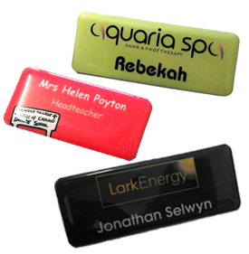 Three rectangular name badges, each with different colors and text, displaying names and roles for individuals at various organizations.