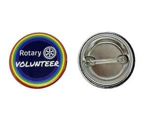 Two round Rotary Volunteer Badges: one features “Rotary VOLUNTEER” with a rainbow border, whilst the other shows the metal pin backing.