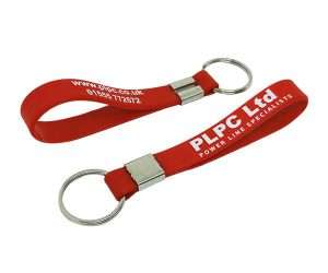 Two red Silicone Band Keyrings with metal rings, featuring the text “PLPC Ltd POWER LINE SPECIALISTS” and contact details printed in white.