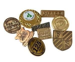 A set of nine Stamped Metal No Colour Badges featuring assorted shapes, engravings, and designs displayed on a white background.