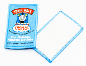 Woven badge showing both front and back; the front features a design of Thomas the Tank Engine with 'Train Walk' in red text at the top.