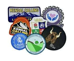 An assortment of Woven Badges featuring diverse designs such as logos, landscapes, animals, and text, displayed in an overlapping arrangement on a white background.