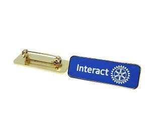 The Rotary Interact Lapel Badges feature a gold pin with a blue rectangular face displaying the word “Interact” and the Rotary International logo; the reverse side includes a pin clasp.