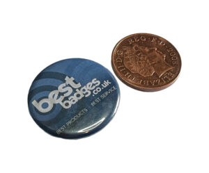 A round blue badge with "bestbadges.co.uk" and a slogan, next to a 2008 UK penny for size comparison.