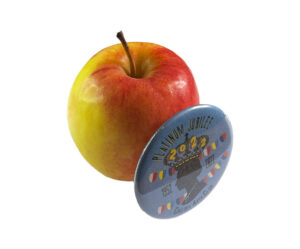 A red and yellow apple with a blue round button in front that reads “PLATINUM JUBILEE 2022” and features a crown design and colorful decorations.