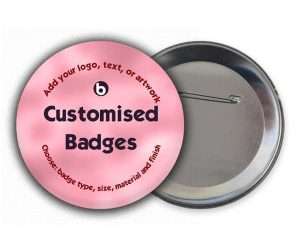 Customised Badges: Round pink badge with black text displaying instructions to add your logo, text, or artwork. The back of the badge features a pin fastening.