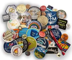 A collection of various badges and patches, including commemorative, school, award, and event designs, arranged overlapping on a white background.