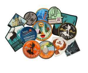 A collection of colorful embroidered patches with various outdoor, swimming, hiking, and adventure-themed designs arranged in a loose cluster on a white background.