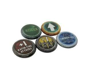 Set of five 25mm Personalised Games Counters, each featuring a unique design: "HIDDEN," an upward arrow symbol, "OBSERVER," "+1 RAPID FIRE ATTACKS," and "+1 DAMAGE VS THIS UNIT"—all displayed on coloured backgrounds.