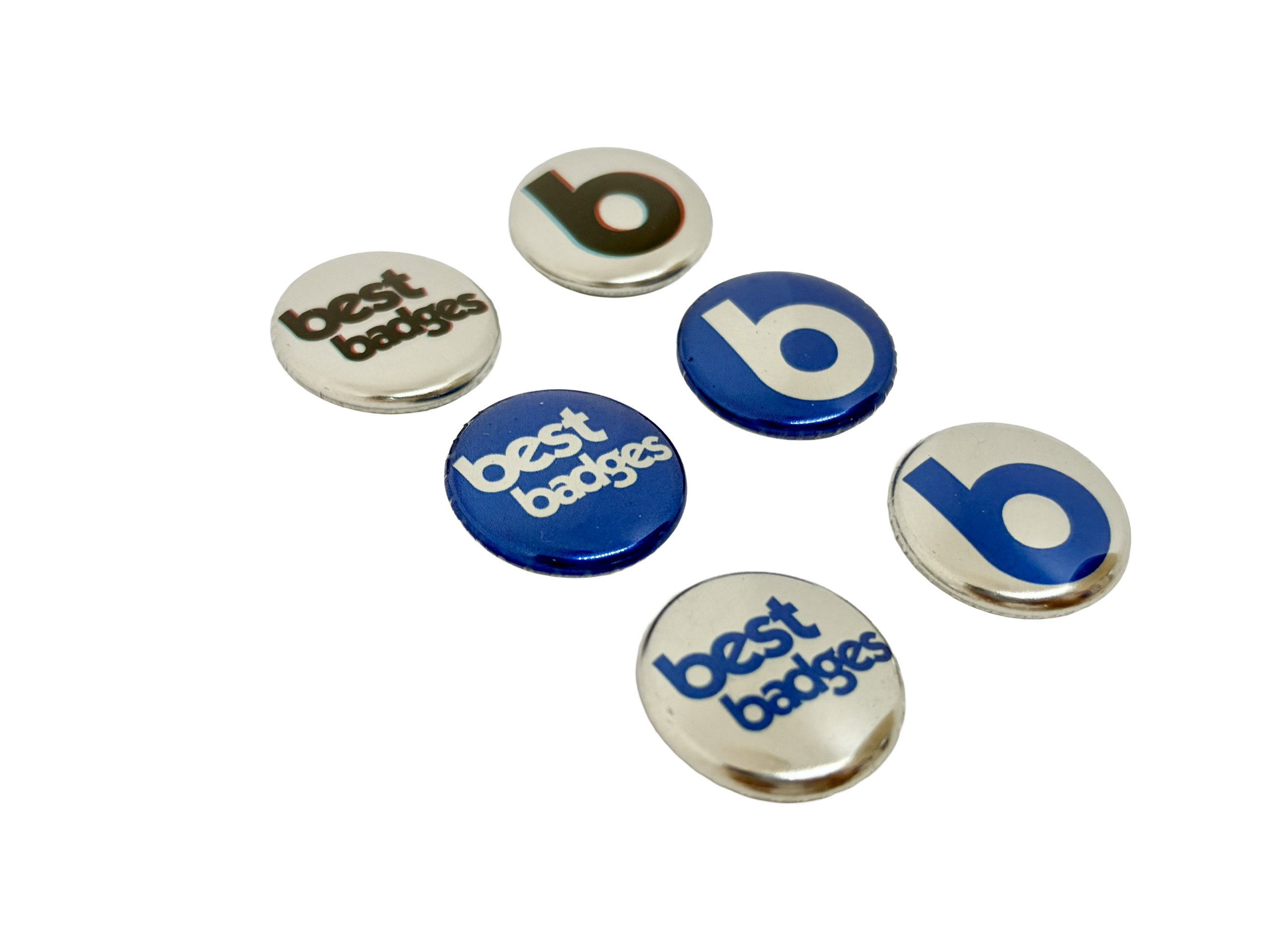 Six Metallic Button Badges—three displaying the text "best badges" and three featuring a lowercase "b," in blue or black on white and blue backgrounds—are arranged on a white surface. Perfect inspiration if you want to design your own button badge.