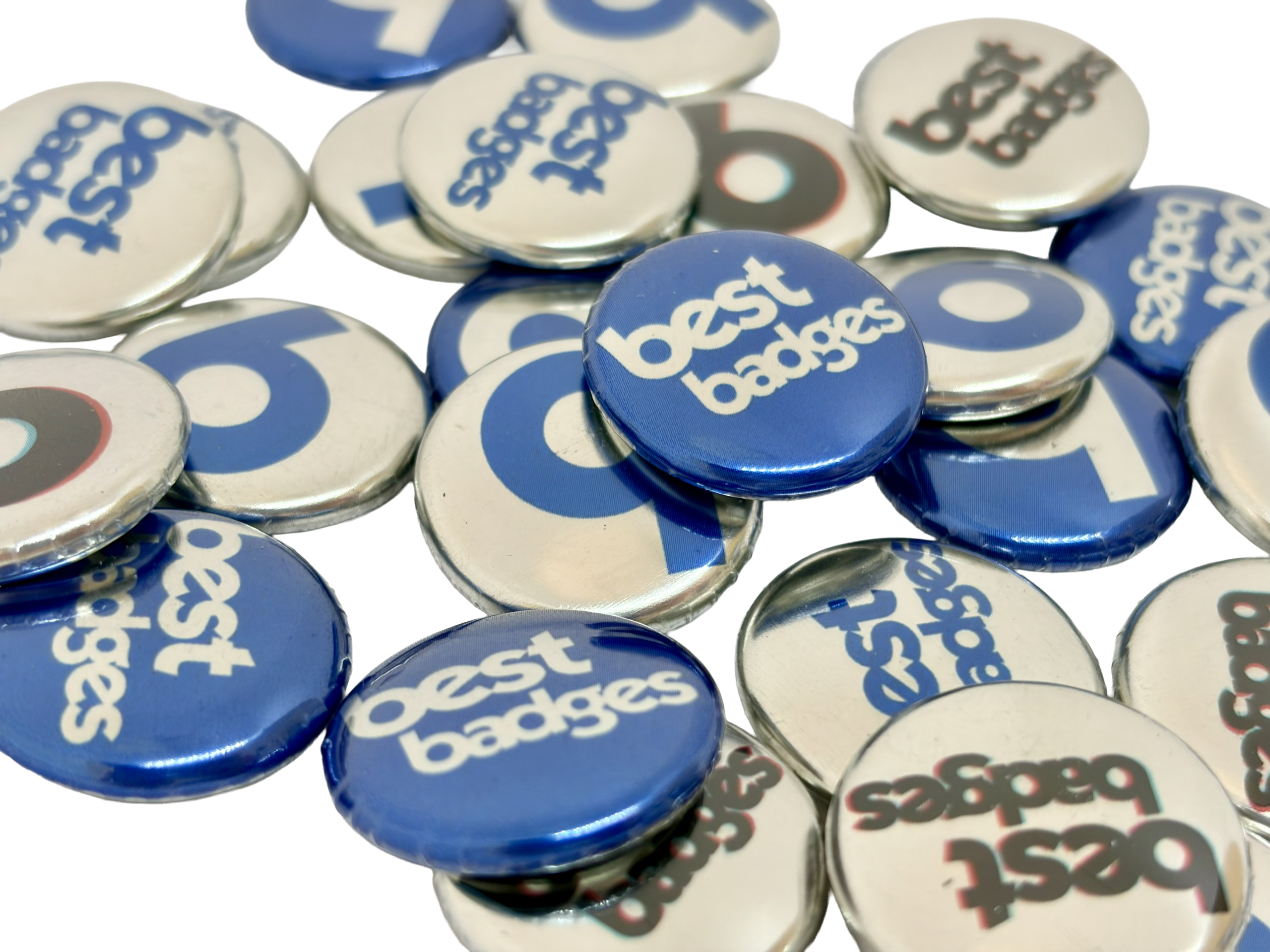 A pile of circular Metallic Button Badges featuring blue and white designs, many boasting the words "best badges" in bold lettering, highlights how simple it is to design your own Metallic Button Badge for a personalised touch.