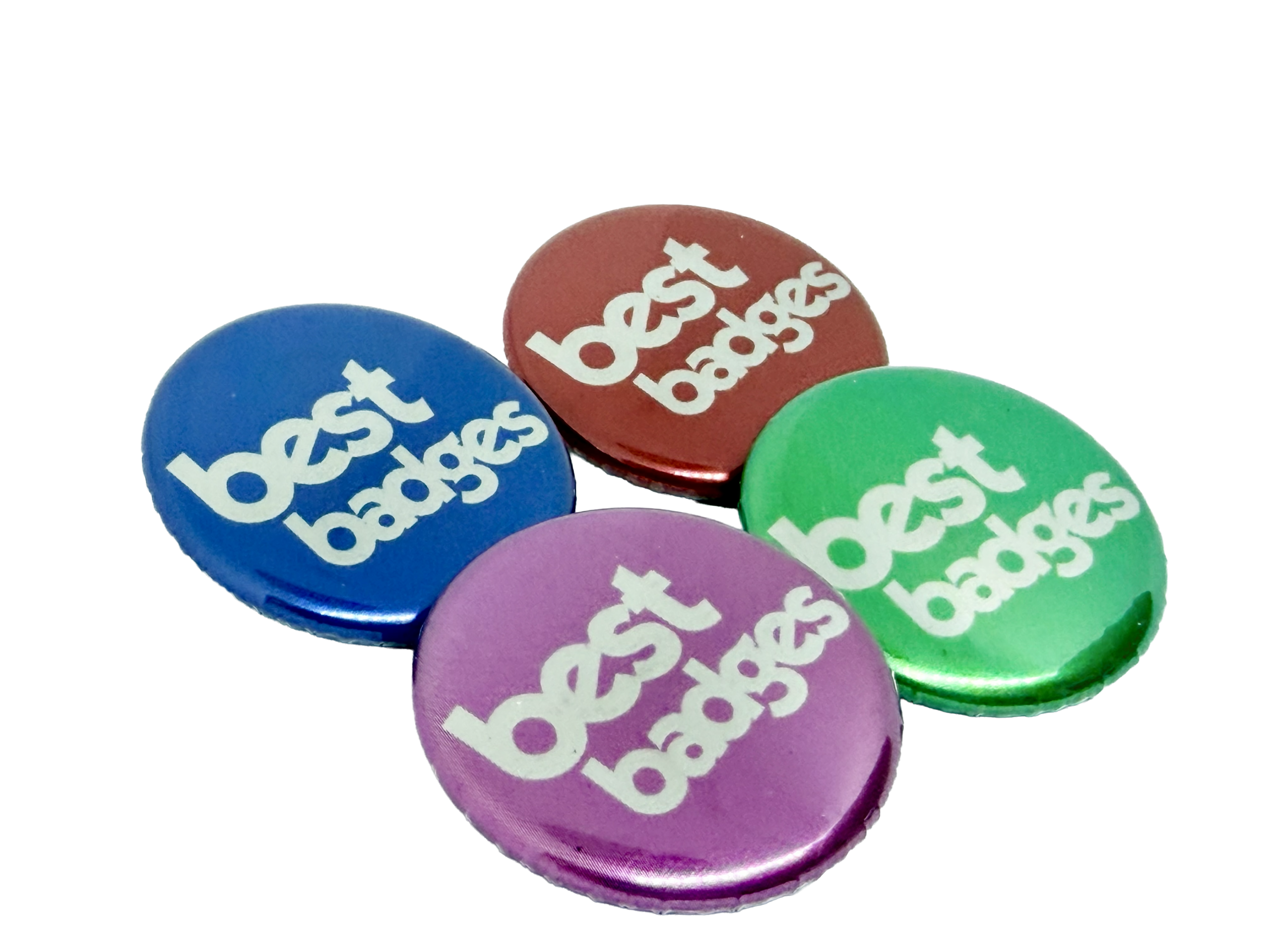 Four round metallic button badges in blue, red, green, and purple, each featuring "best badges" printed in white lowercase letters—perfect inspiration if you want to design your own button badge.