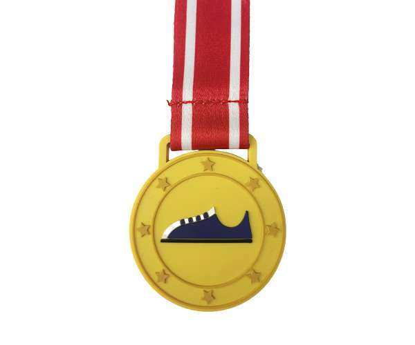 A Soft PVC Medal in gold, featuring a trainer icon at the centre and finished with a red-and-white striped ribbon attached.