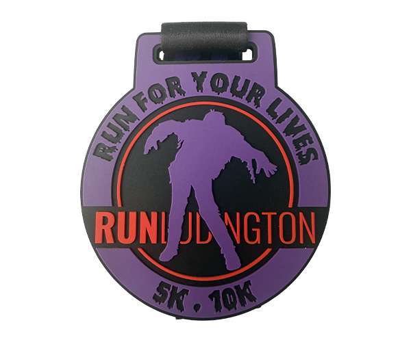 A Soft PVC Medal in purple and black featuring a zombie silhouette, with "Run For Your Lives RUNDUDINGTON 5K, 10K" encircling the design.